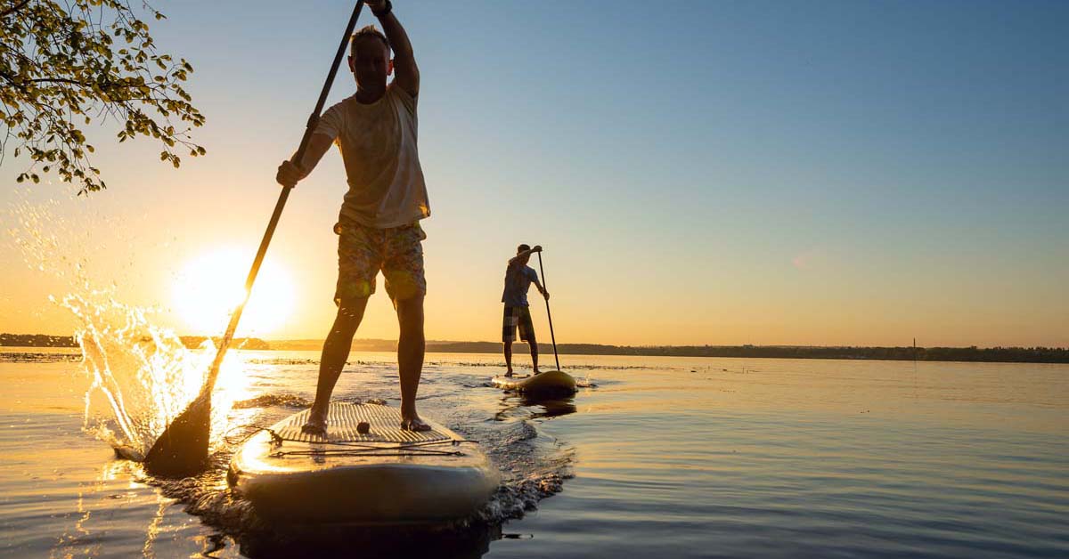 Two men paddle boarding on a lake 