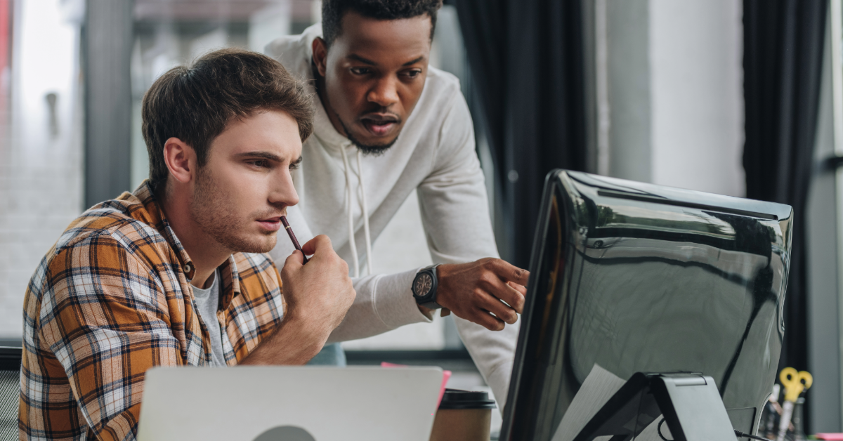 Two colleagues with a concerned expression, looking at a computer screen. 