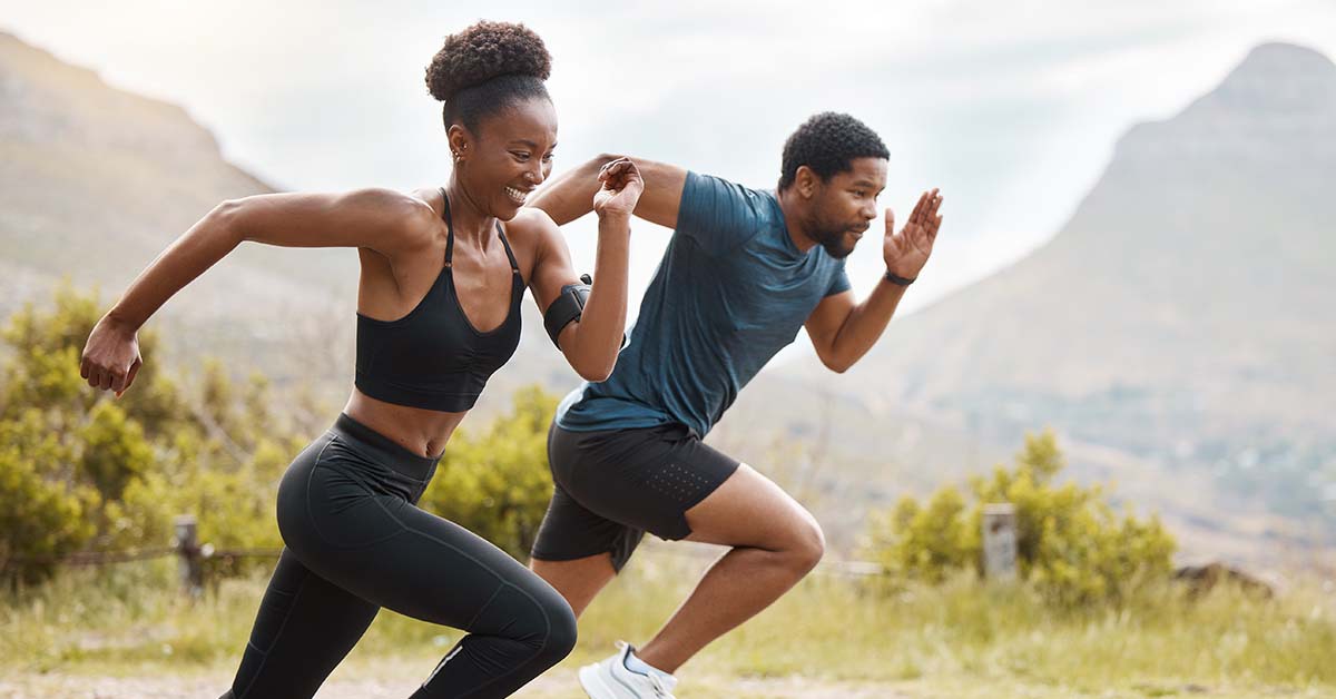 A man and a woman running in front of mountains