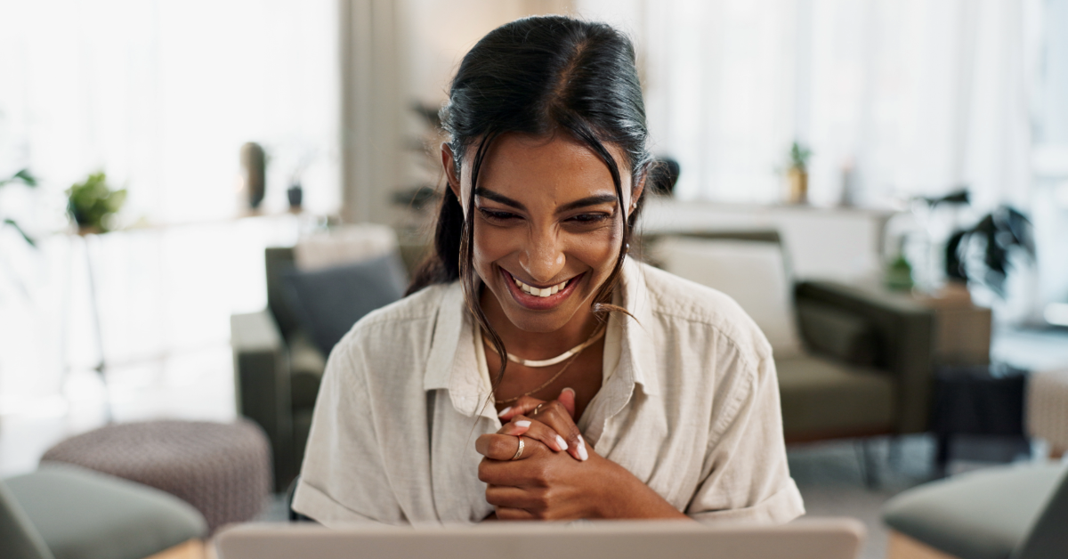 Woman smiling at laptop using online banking for share certificate