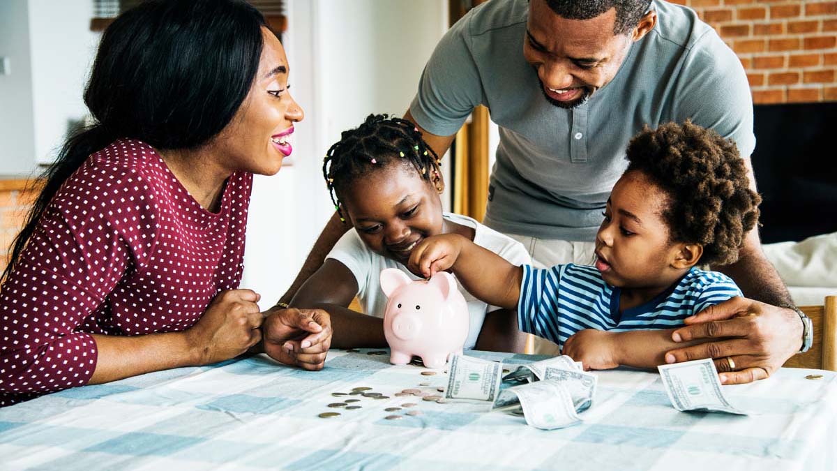 Family smiling with children putting coins into a piggy bank