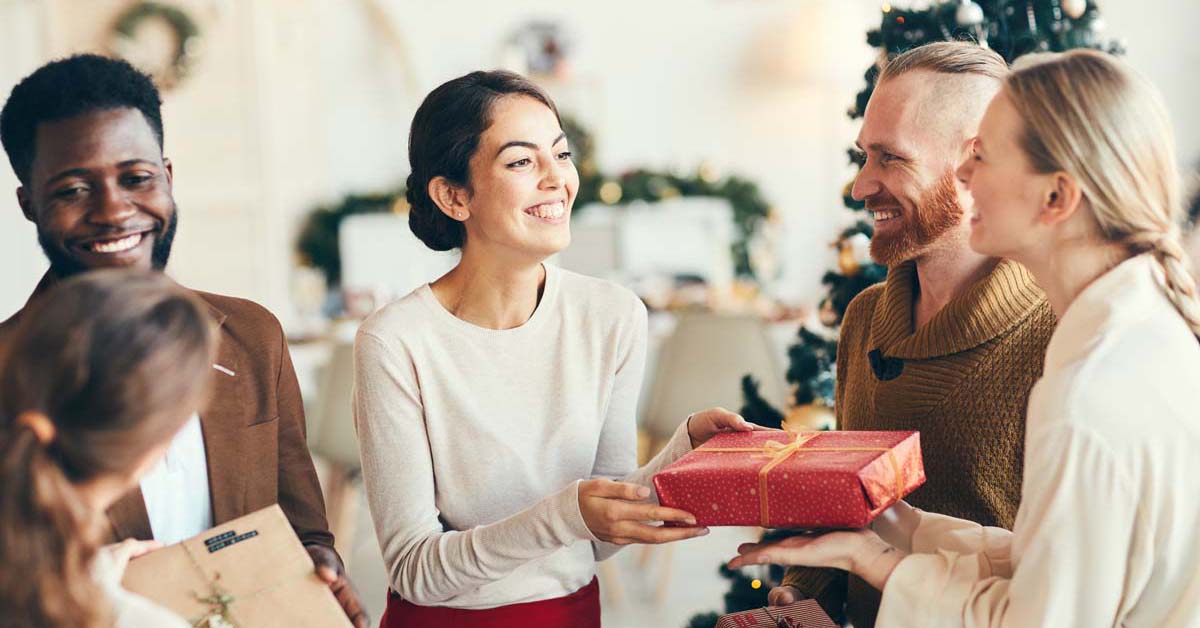 Group of smiling friends exchanging holiday gifts 