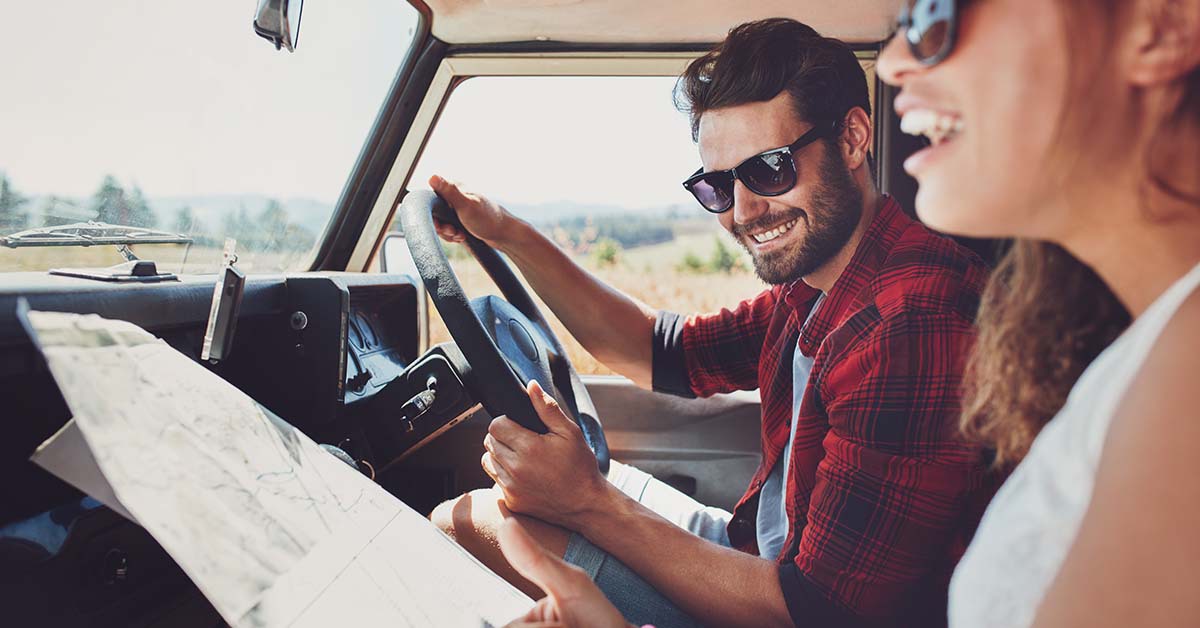 Man and woman driving in a car on a road trip 