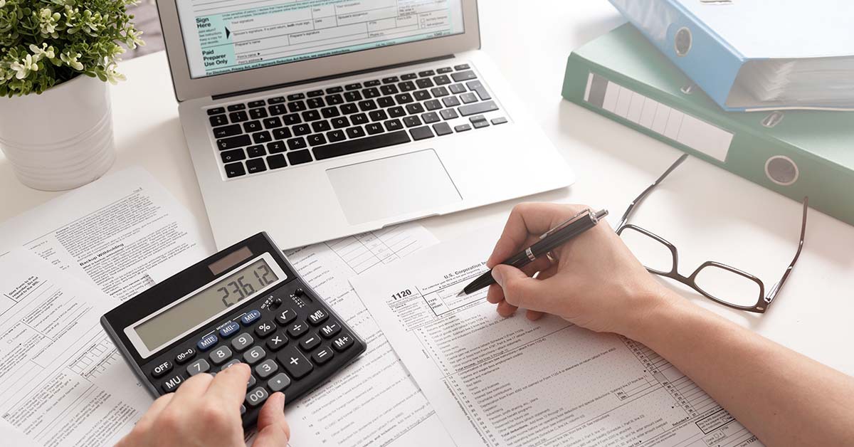 Person completing their taxes using their laptop and calculator